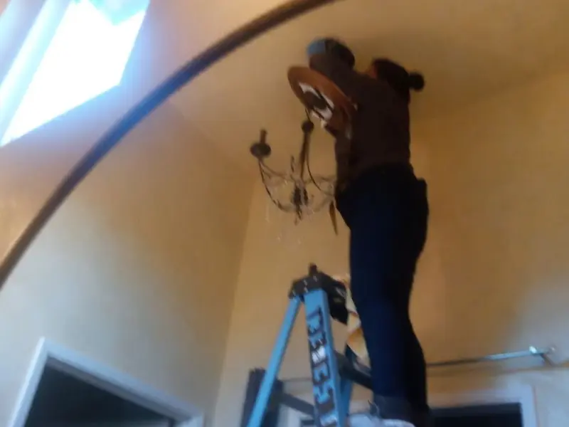 Electrician installing a chandelier in a Milton residence